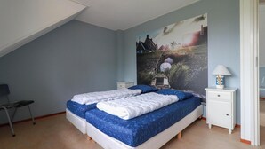 A bedroom with two beds, a nightstand, a lamp, and a painting on the wall. - Detached Dune Villa With Hot-tub (Makkum)