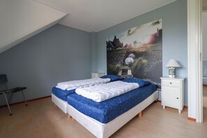 Ein Schlafzimmer mit zwei Betten, einem Nachttisch, einer Lampe und einem Gemälde an der Wand.