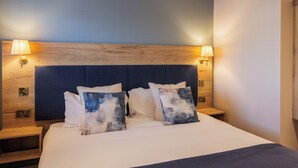 A hotel room with a large bed, two bedside tables, and a headboard with integrated wall sconces. - The Boat Inn (Oughterard)