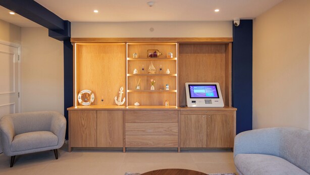 A modern living room with a wooden entertainment unit, a television, and two sofas. - The Boat Inn (Oughterard)