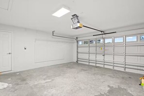 Eine Garage mit Betonboden, einer weißen Tür und einer Garage mit Fenstern.