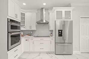 A modern kitchen with white cabinetry, stainless steel appliances, and a marble floor. - Modern Boutique House/Heated Pool/Clearwater/Tampa (Tampa)