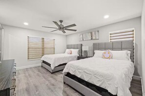 Ein Schlafzimmer mit zwei Betten, einem Deckenventilator und einem Fenster mit Jalousien.