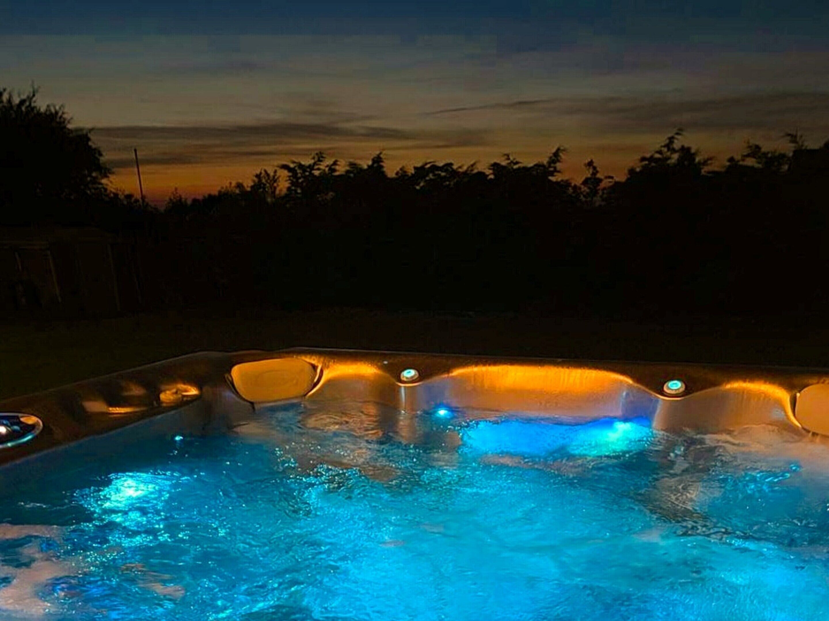 A hot tub with illuminated edges and a clear view of the sky.