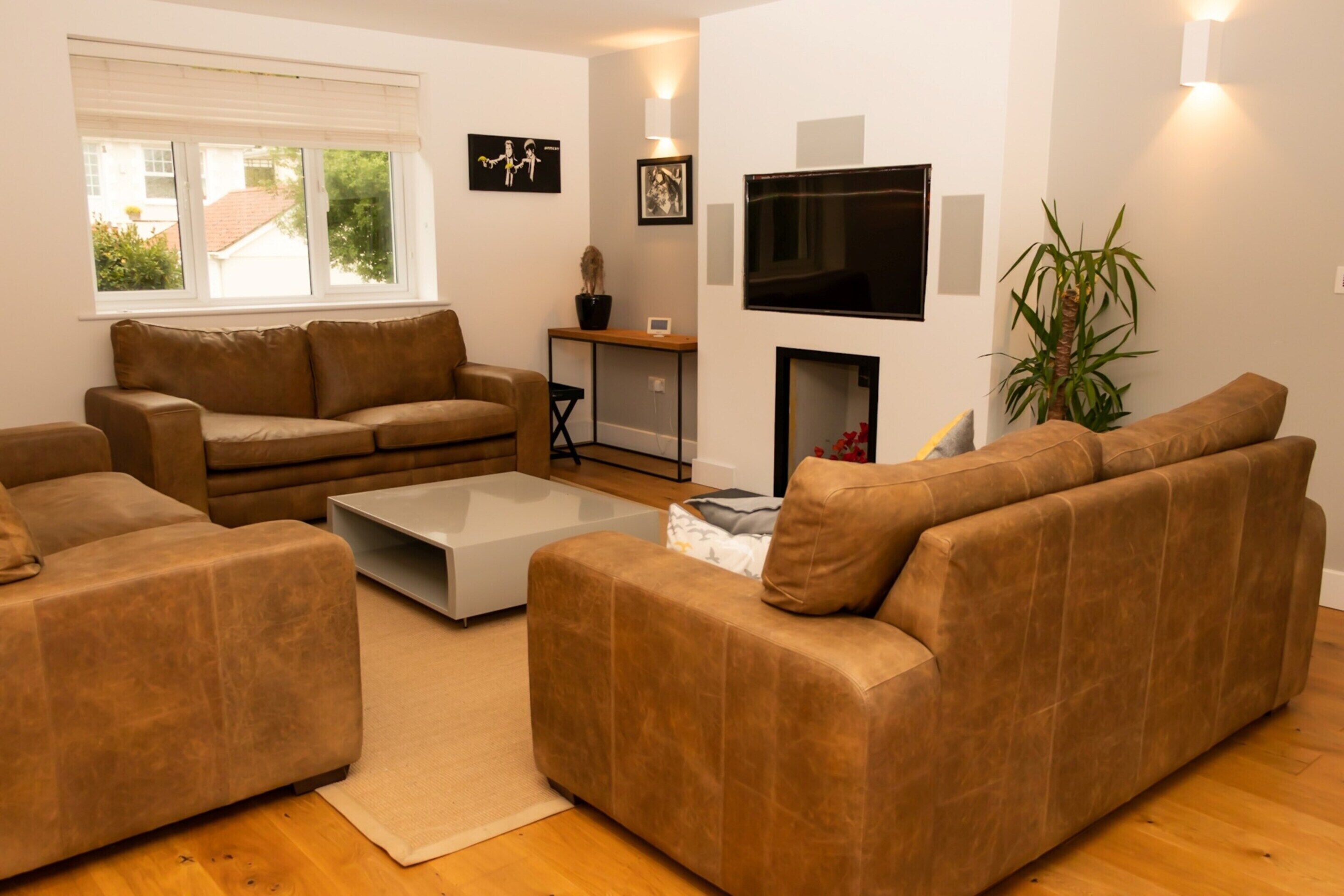 A living room with brown sofas, a coffee table, a TV, and a plant.