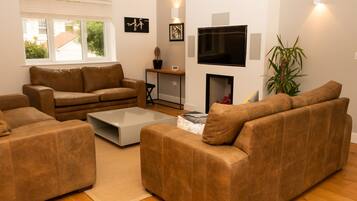 A living room with brown sofas, a coffee table, a TV, and a plant.