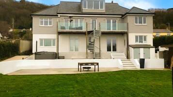 A two-story house with a front staircase, a small patio, and a grassy yard.