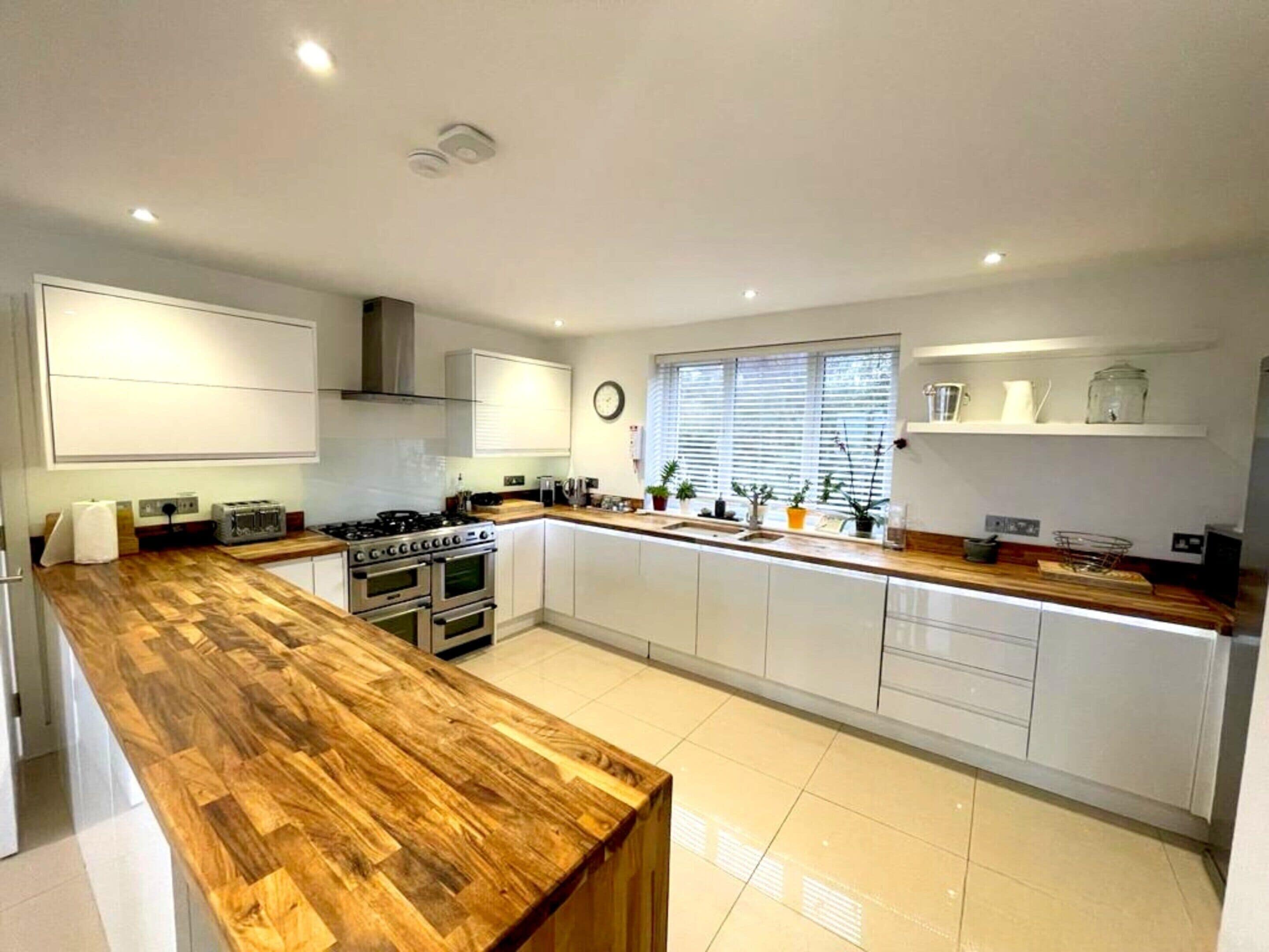 A modern kitchen with a wooden countertop, built-in oven, and white cabinetry.