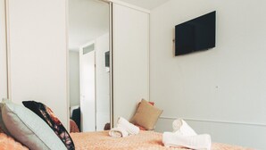 Een slaapkamer met een bed, een kledingkast, een televisie en een spiegel.
