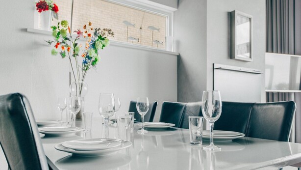 Een eethoek met een tafel voor zes personen, compleet met borden, glazen en bestek.