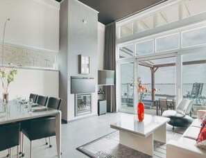 Ein modernes Wohnzimmer mit Essbereich, Kamin, großem Fenster und Aussicht sowie einer Sitzecke mit Blick.
