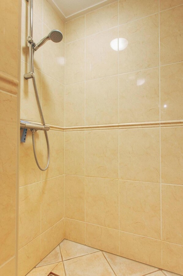 A corner of a bathroom with beige tiles, a showerhead, and a handheld shower attachment. - Deluxe Dike Villa With Sauna for 6 (Makkum)