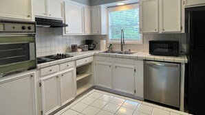 A kitchen with white cabinets, a stove, a microwave, and a dishwasher. - Spacious 4-bedroom house in gorgeous Houston with AC (Houston)