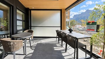 An outdoor seating area with a table and chairs, a projector screen, and a view of a construction site with mountains in the background.