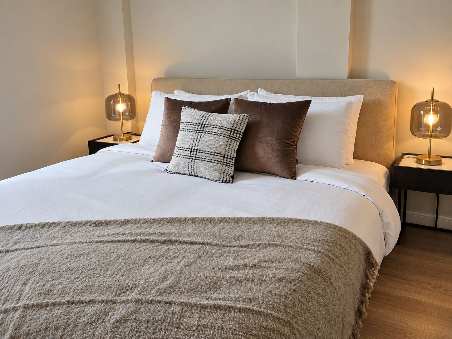 A neatly made bed with a white duvet, two pillows, and a textured throw blanket.
