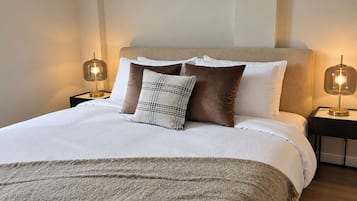 A neatly made bed with a white duvet, two pillows, and a textured throw blanket.