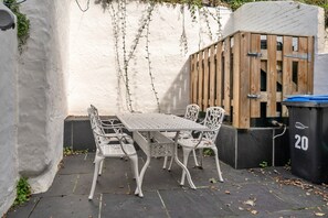 An outdoor patio with a white metal table and chairs, a wooden fence, and a black trash bin labeled '20'. - Exmoor Retreat Near the Harbor (Lynmouth)