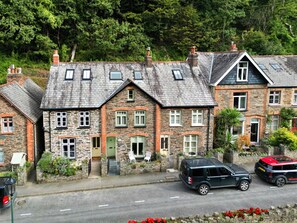 A row of stone houses with a paved driveway and parked cars. - Exmoor Retreat Near the Harbor (Lynmouth)