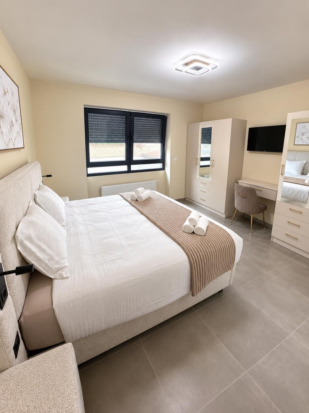 A modern bedroom with a bed, a desk, and a wardrobe.