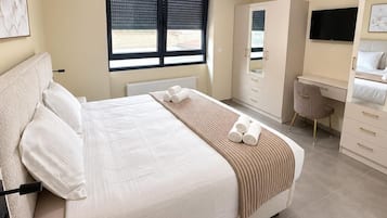 A modern bedroom with a bed, a desk, and a wardrobe.