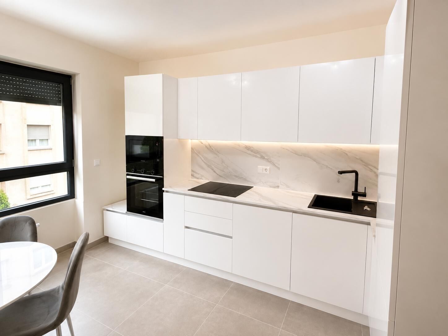 Une cuisine moderne avec des meubles blancs, un plan de travail noir et un four encastré.