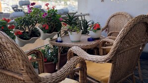 A wicker table set with chairs, potted plants, and a decorative mirror on a balcony with a city view. - Spacious SeaView Apartment in the heart of Saranda (Saranda)