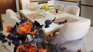 A modern kitchen with white cabinets, a wooden countertop, and a dining area with a white table and chairs. - Spacious SeaView Apartment in the heart of Saranda (Saranda)