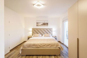 Ein Schlafzimmer mit Bett, Nachttischen, Kopfteil, einem Bild und einem Fenster.