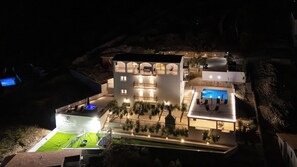 A multi-story building with a rooftop pool, outdoor seating, and a well-lit terrace.
