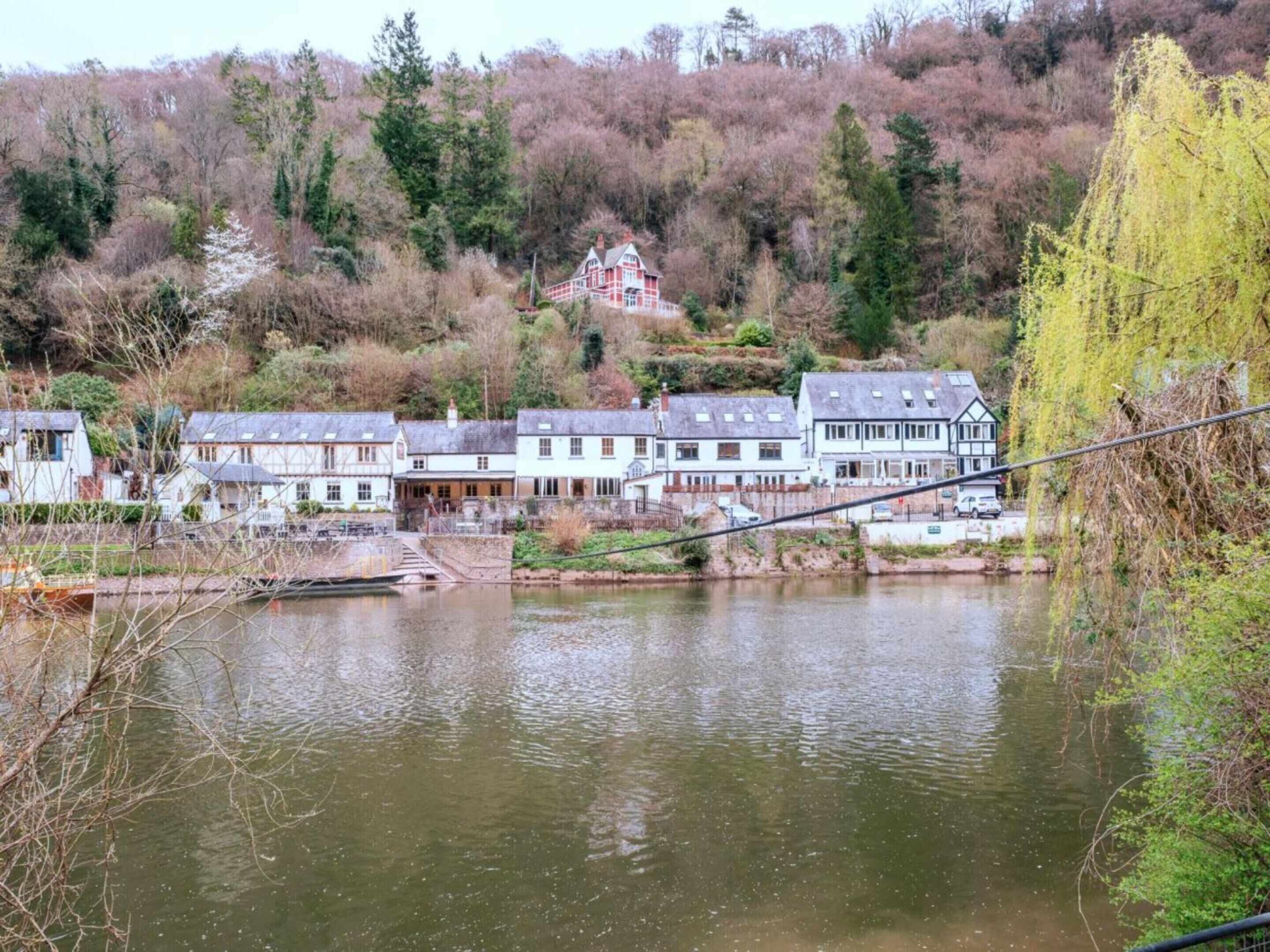 Une vue sur la rivière, avec une rangée de maisons traditionnelles et un pont qui enjambe l’eau.