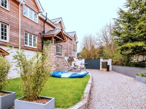 A residential property with a stone wall, a blue inflatable pool, and a gravel driveway. - Contemporary Cornwall Retreat for Groups (Ross-on-Wye)