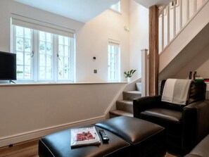 Ein Wohnzimmer mit einer Couch, einem Couchtisch, einem Fernseher und einer Treppe.