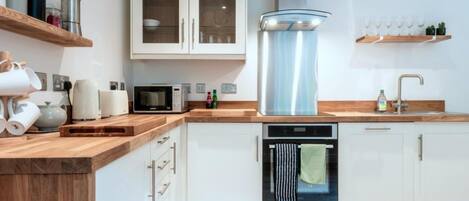 Una cocina moderna con armarios blancos, extractor de acero inoxidable, microondas y lavavajillas.