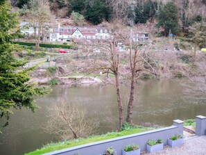 A riverside view with a building labeled 'ROYAL' in the background, a bridge, and a row of planters along the riverbank. - Contemporary Cornwall Retreat for Groups (Ross-on-Wye)