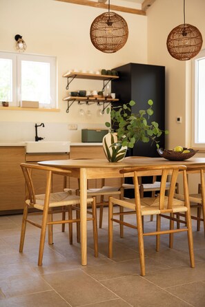 Une table de salle à manger en bois, avec des chaises, une plante en pot et un saladier rempli de fruits.