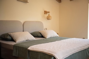 Un lit avec une couvre-lit verte et des oreillers, une lampe fixée au mur et un élément de décoration murale à texture.