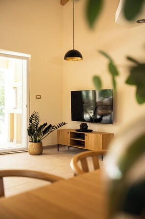 A modern living room with a television mounted on the wall, a wooden cabinet, and a potted plant. - Villetta Malner – Luxury Villa with Private Pool (Garica)