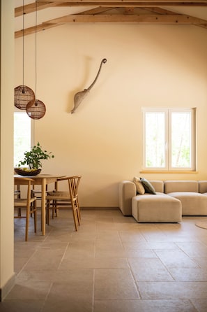 Une pièce comprenant une table à manger, des chaises, un canapé et une fenêtre laissant entrer la lumière naturelle.