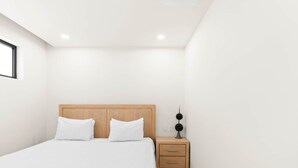 A minimalist bedroom with a bed, bedside table, and a wall-mounted light fixture. - D436 - Lovely apartment with balcony & lagoon view (Cole Bay)