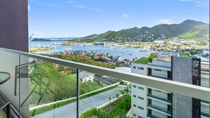 A balcony with a view of a marina, buildings, and a hilly landscape. - D436 - Lovely apartment with balcony & lagoon view (Cole Bay)