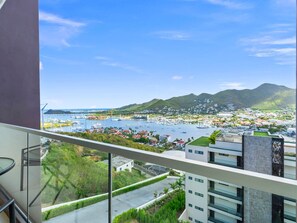 A balcony with a view of a marina, buildings, and a hilly landscape. - D436 - Lovely apartment with balcony & lagoon view (Cole Bay)
