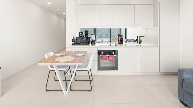 A modern kitchen with white cabinetry, a built-in oven, and a dining area with a table and chairs. - D436 - Lovely apartment with balcony & lagoon view (Cole Bay)