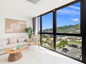 A modern room with a large window, a sofa, a chair, and a coffee table. - A135 - Beautiful one bedroom apartment (Cole Bay)