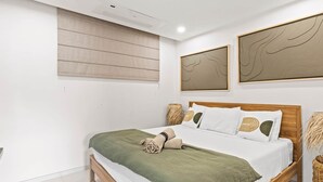Um quarto moderno com cama de madeira, roupa de cama branca e arte abstrata na parede.