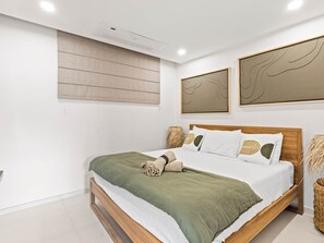 Ein modernes Schlafzimmer mit einem hölzernen Bett, weißer Bettwäsche und abstrakter Wandkunst.
