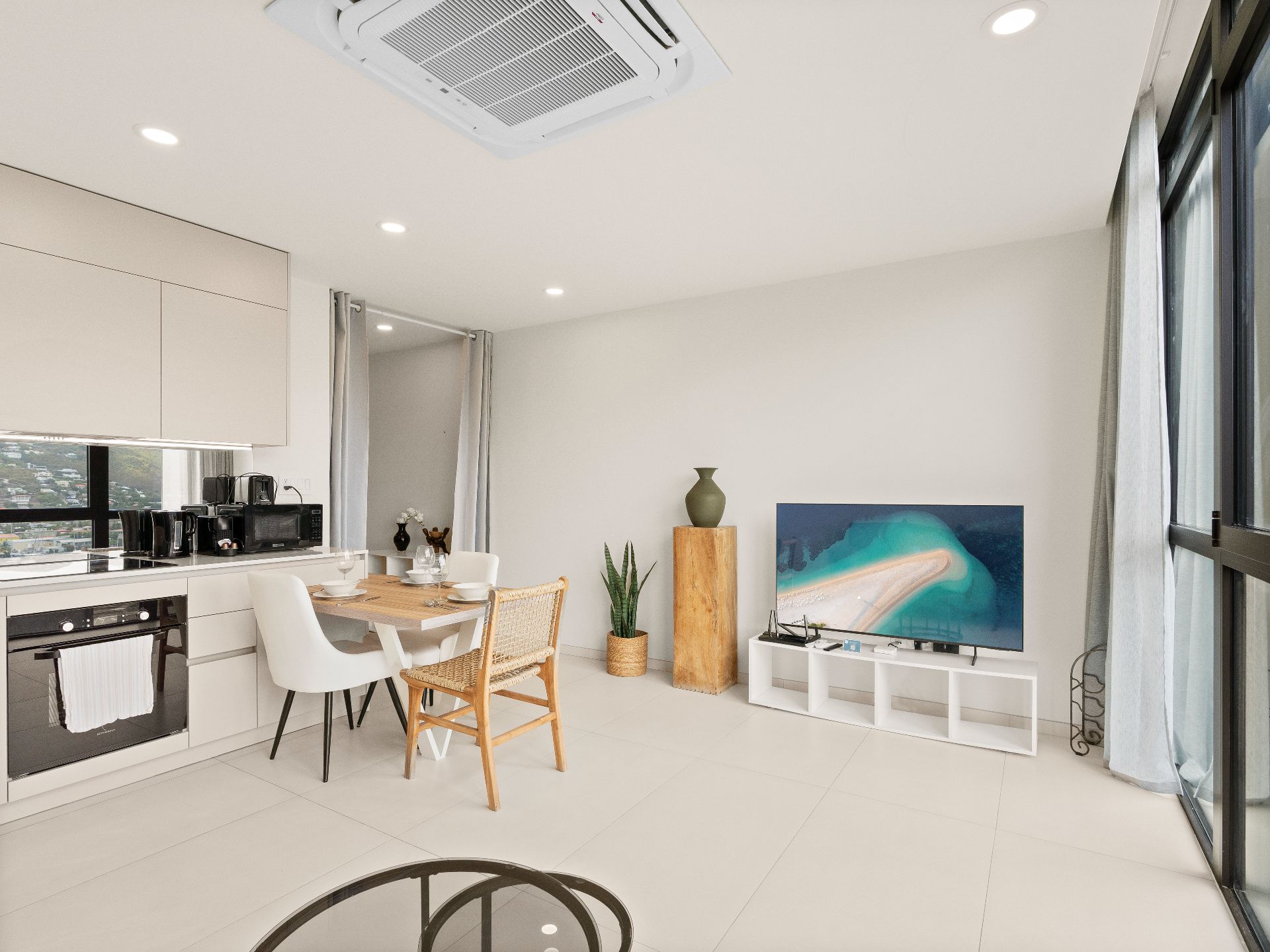Una cocina moderna con comedor, televisor de pantalla plana y un amplio ventanal.