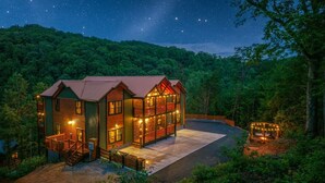 A two-story log cabin with a balcony, surrounded by forest. - Chrome&Timber|Pool|Sauna|HotTub|FirePit|Sleeps 33 (Sevierville)