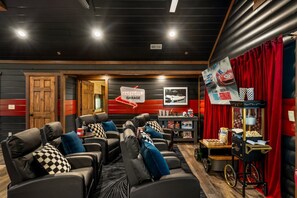 Ein Heimkino mit mehreren Sitzbereichen, einer Popcornmaschine und einem roten Vorhang als Hintergrund.