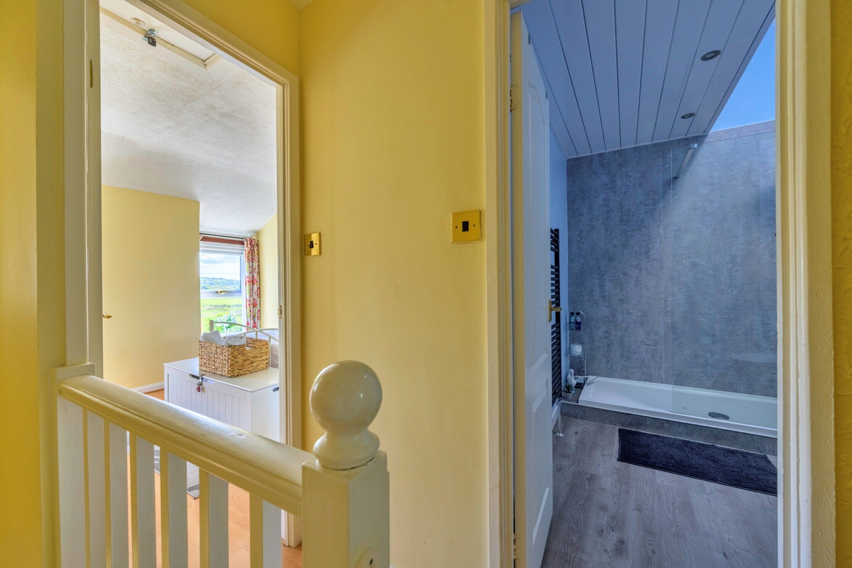 A hallway leading to a bathroom with a shower and a view of the outdoors.