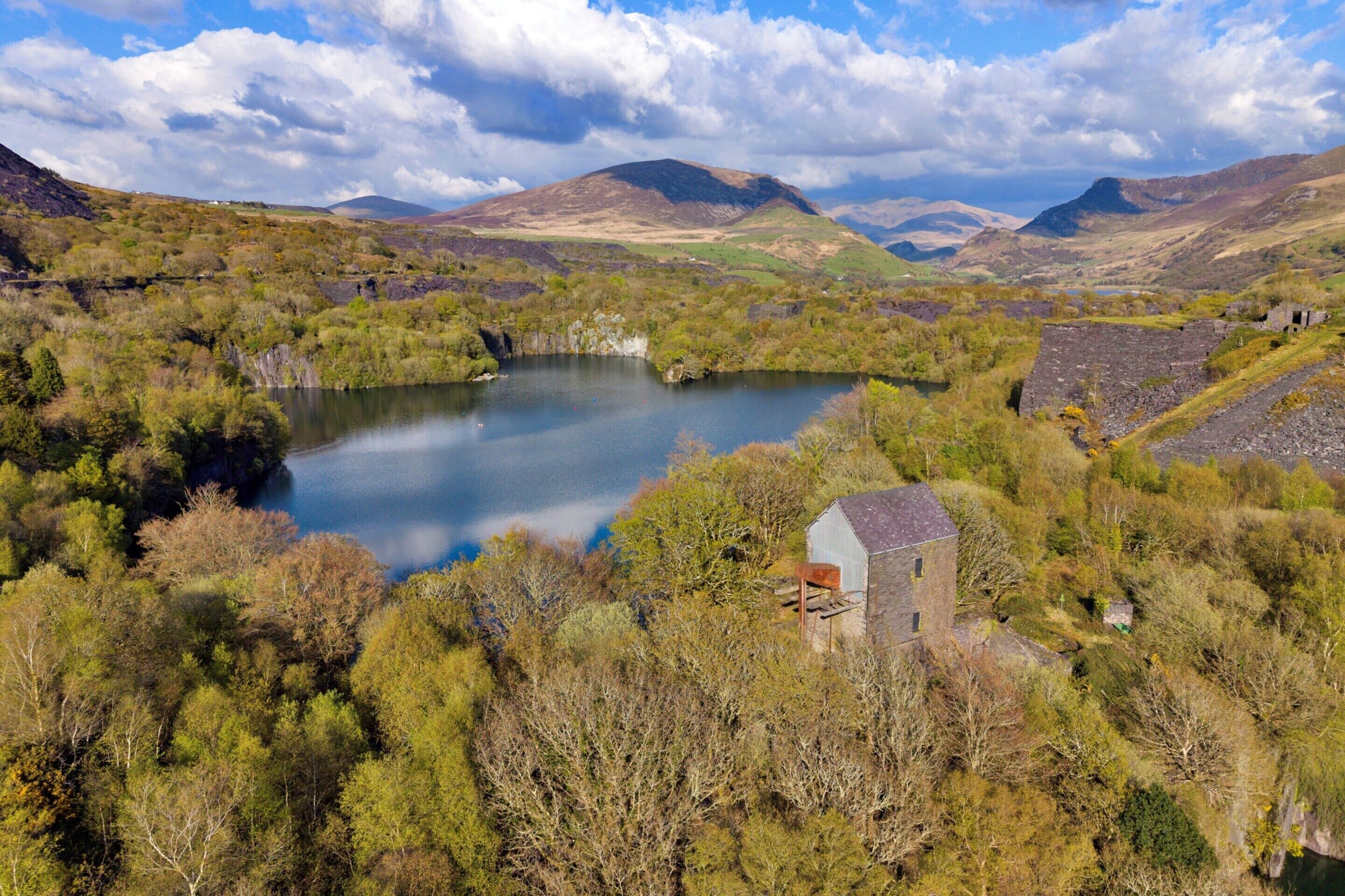 A rural landscape with a lake, a small building, and surrounding hills.